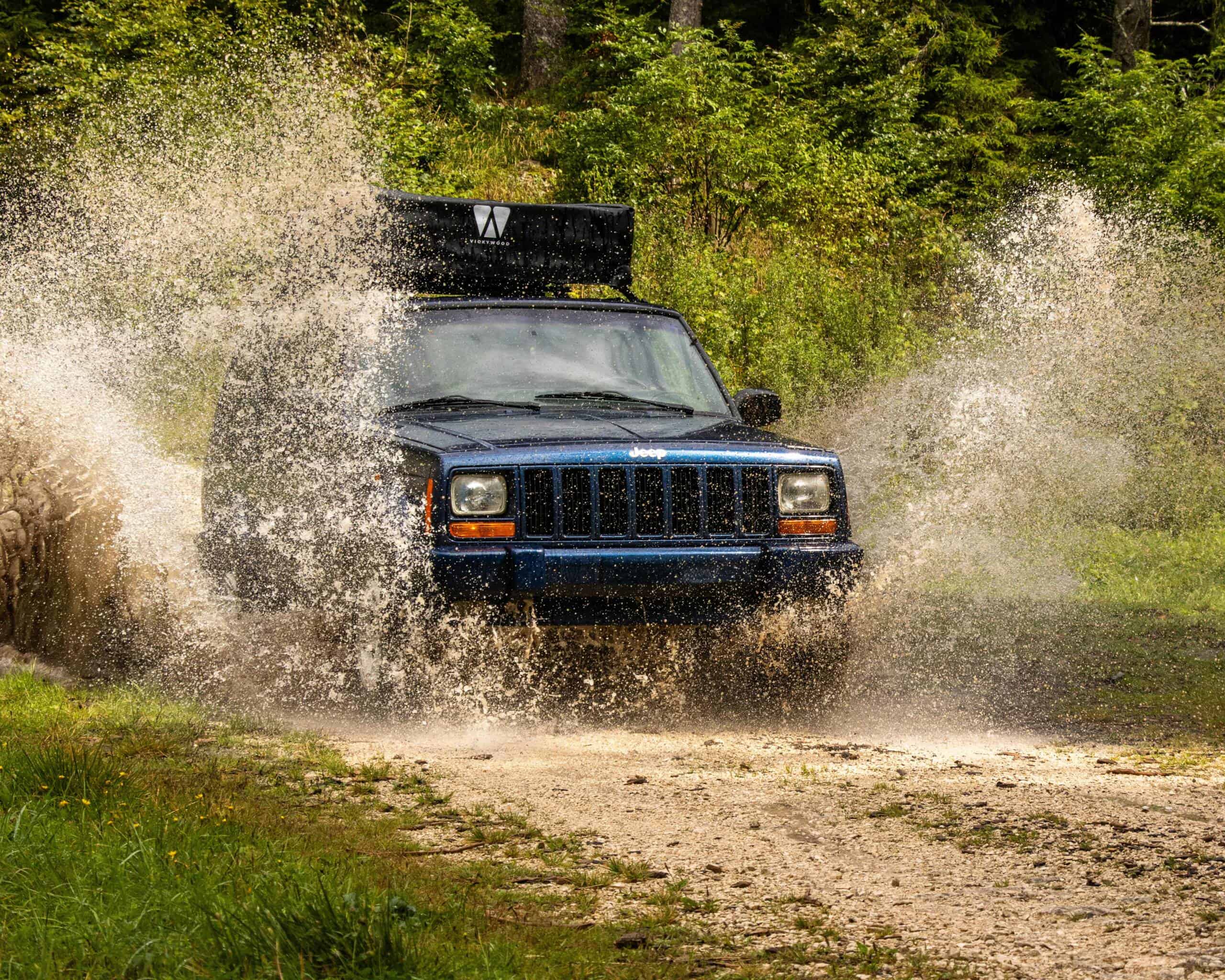 Geländewagen fährt durch Wasserpfütze im Wald.