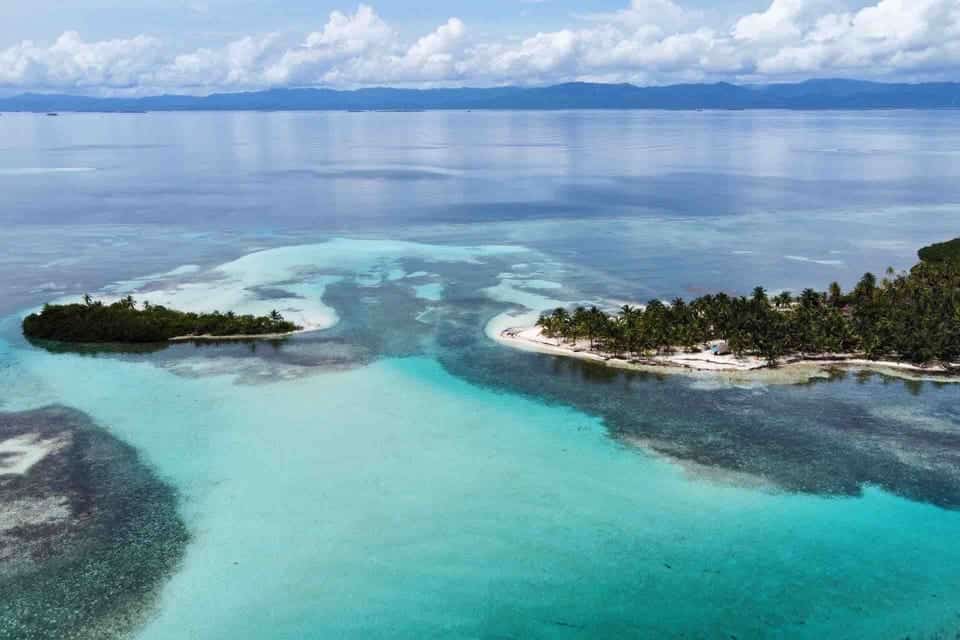 Blick auf die San Blas Inseln mit türkisfarbenem Wasser und Palmen.