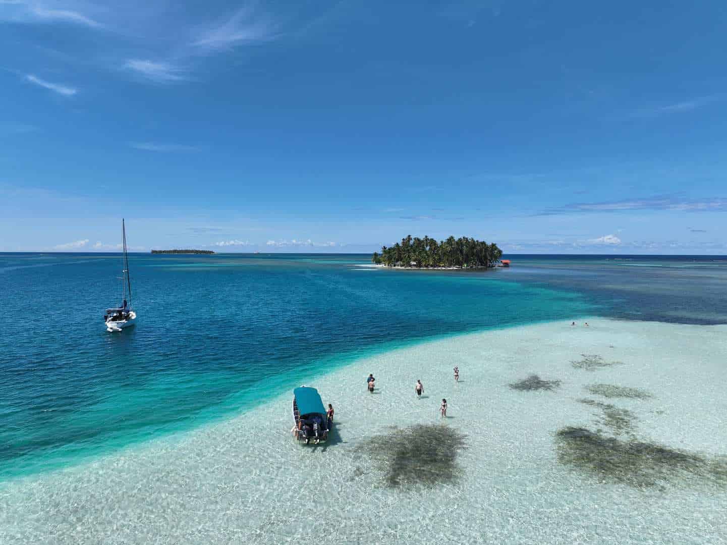 San Blas Inseln, Panama, Karibik, türkisfarbenes Wasser, Strand, Segelboot, Insel im Hintergrund.