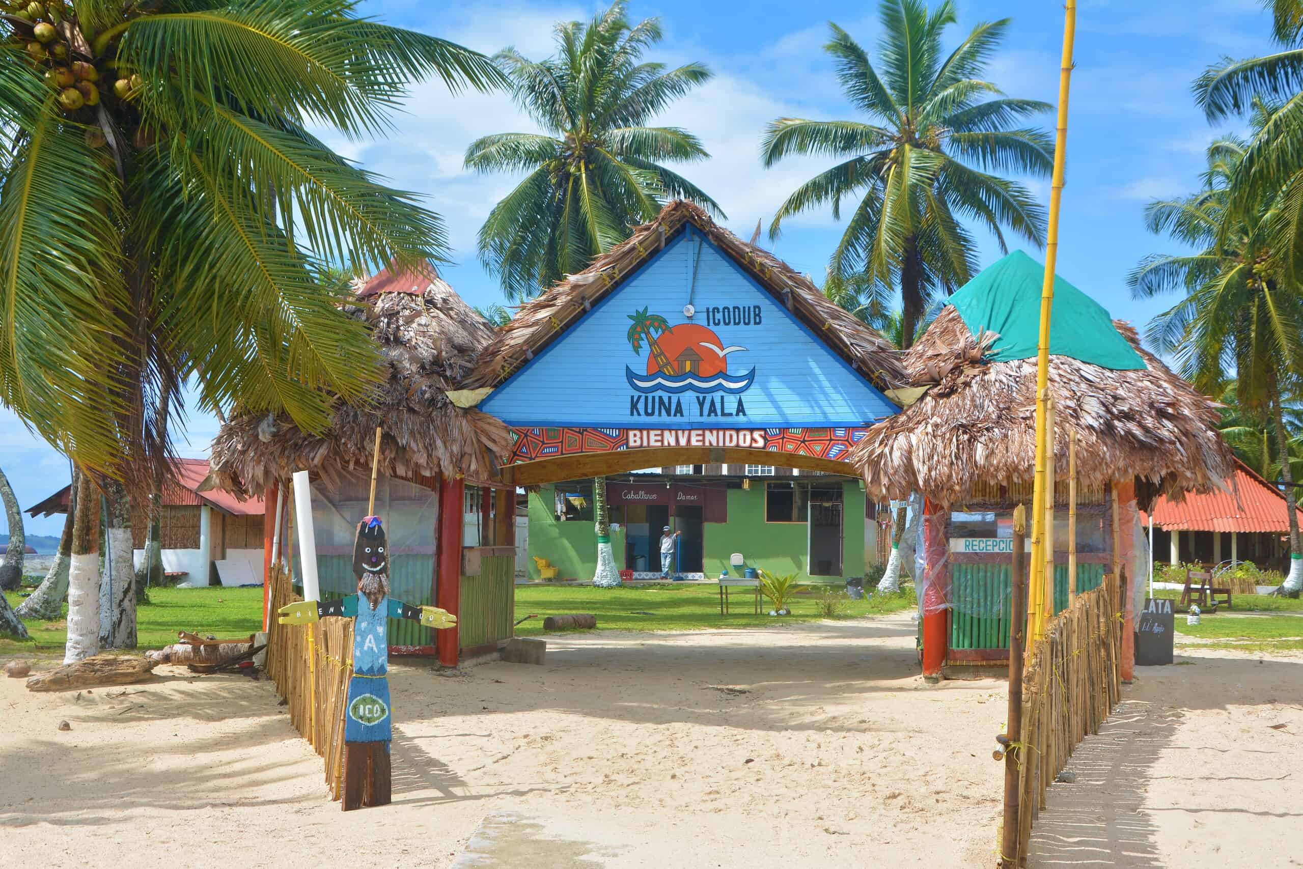 Eingang zum Kuna Yala Touristenort auf den San Blas Inseln, Panama, mit Palmen und Strand.