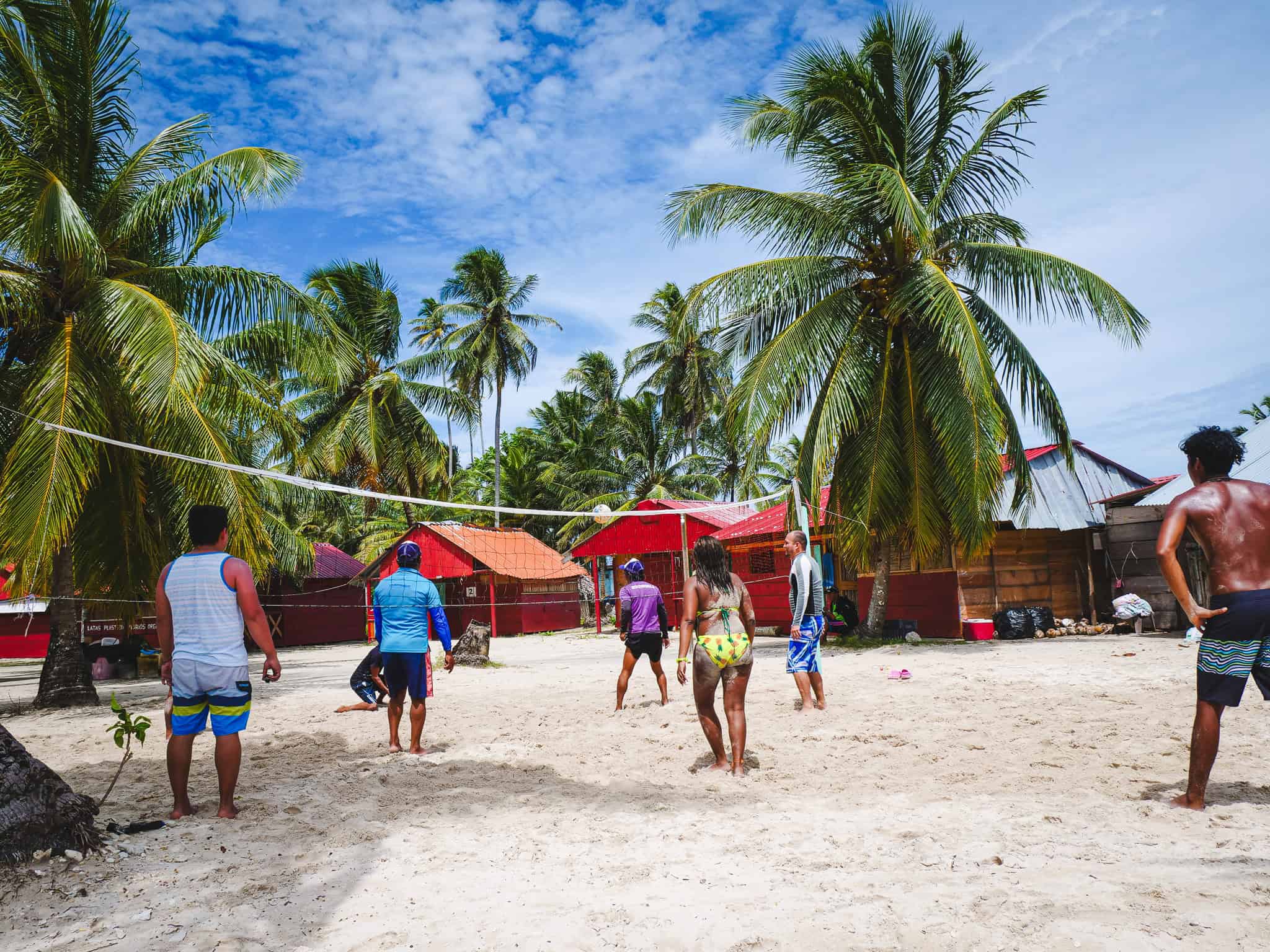 Menschen spielen Volleyball auf Sandstrand mit Palmen in Guna Yala, Panama.