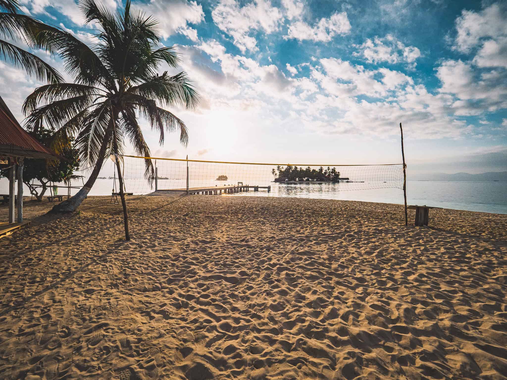 Sandstrand mit Palmen, Volleyballnetz und Blick auf das Meer in Guna Yala, Panama.
