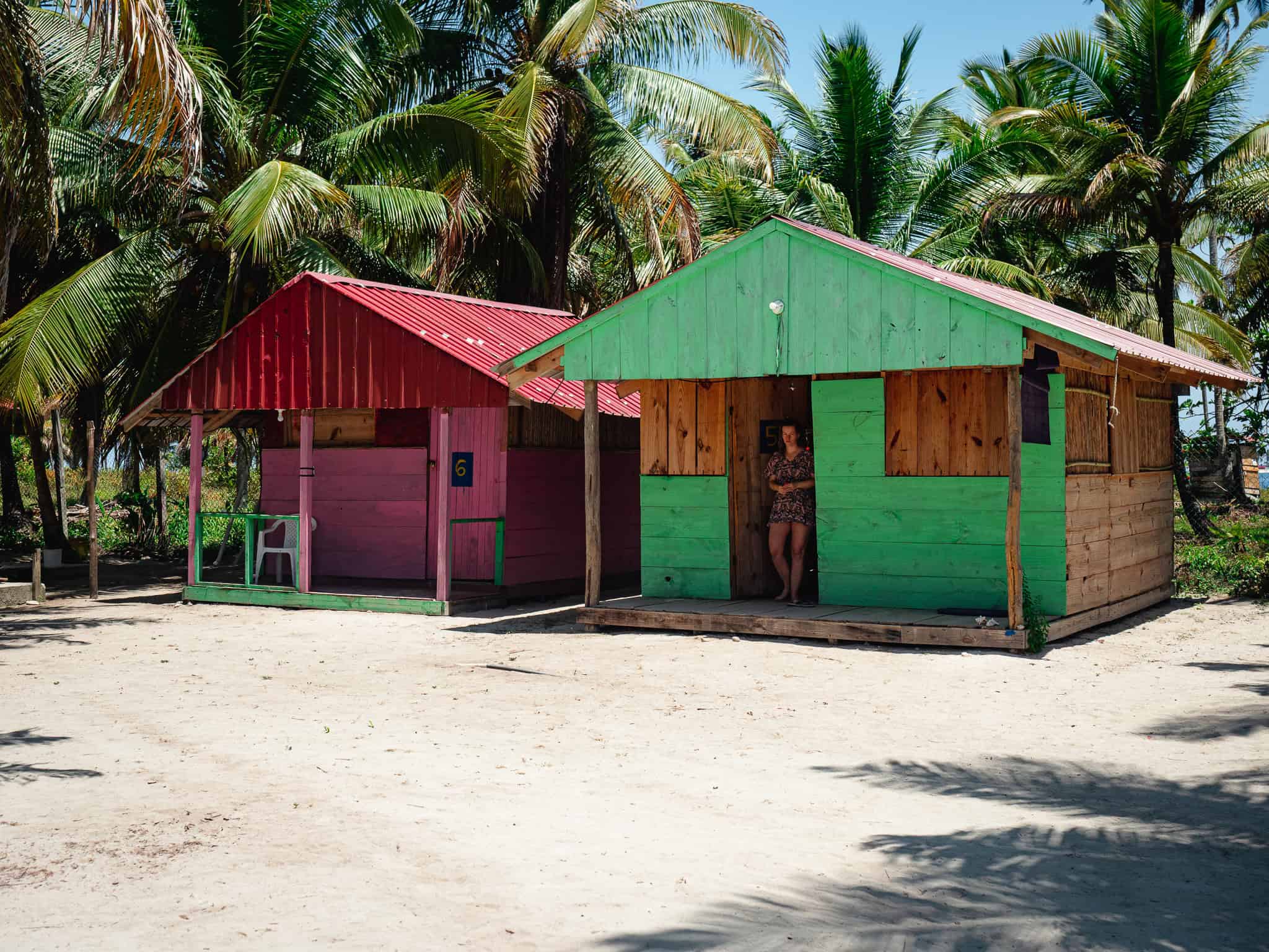 Bunte Holzhütten auf Sandstrand mit Palmen in Guna Yala, Panama.