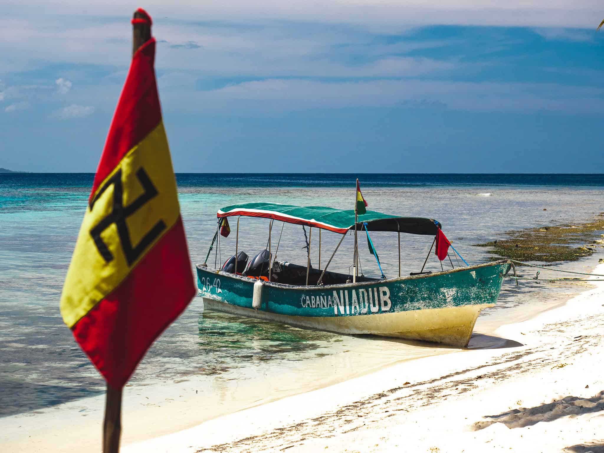 Boot am Strand der San Blas Inseln Boot am Strand der San Blas Inseln, Panama, mit Guna Yala Flagge im Vordergrund.
