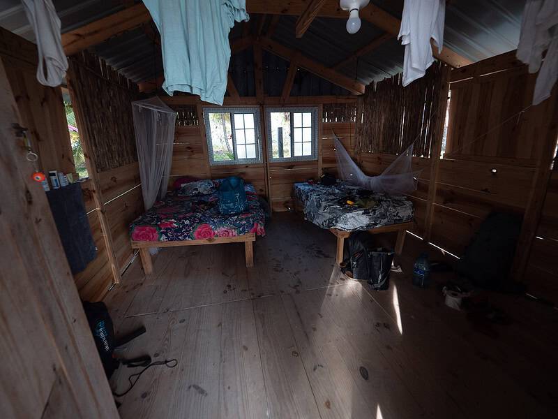 Innenansicht einer Holzhütte auf den San Blas Inseln, Panama, mit Bett und Fenster.