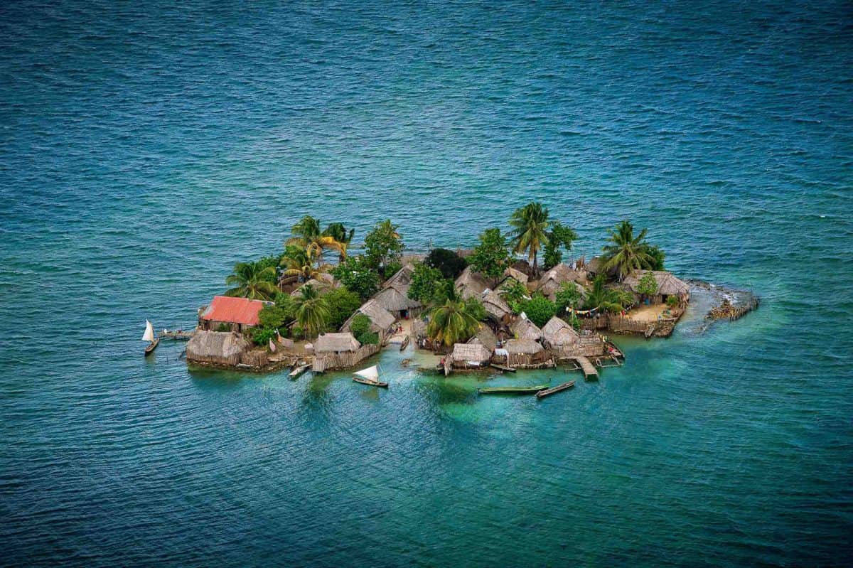 Kleine Insel mit Palmen, Häusern und Booten in den San Blas Inseln, Panama.